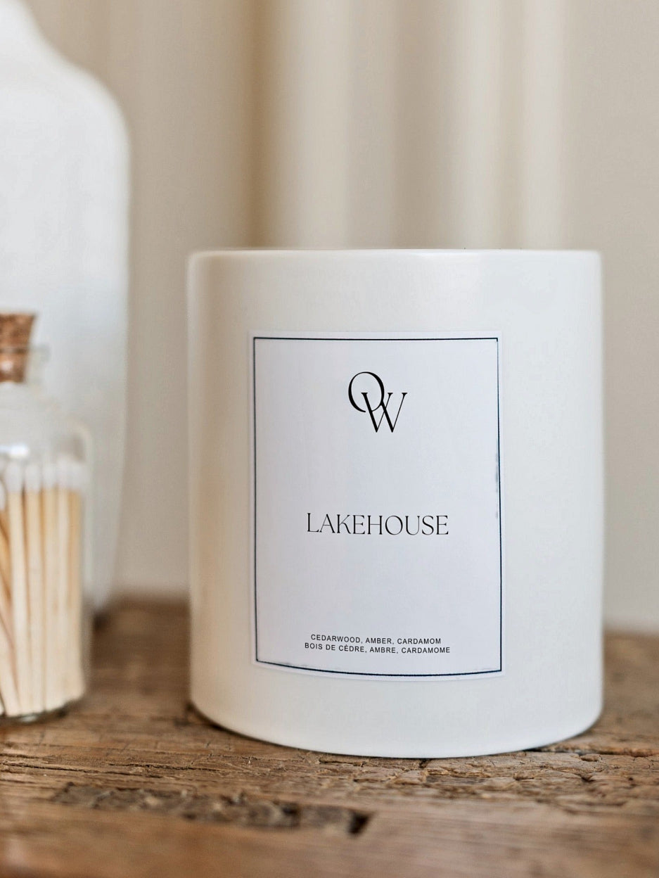 White Lake House candle beside a glass jar of matches on a wooden table.